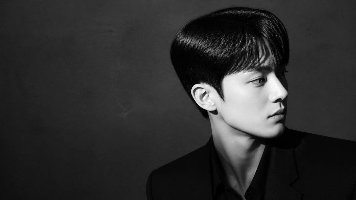 Black and white editorial portrait of a man with sleek, flat side hair